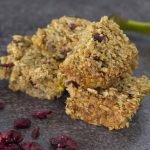 fruity vegan flapjacks on a grey blackground with dried cranberries and a banana on the side
