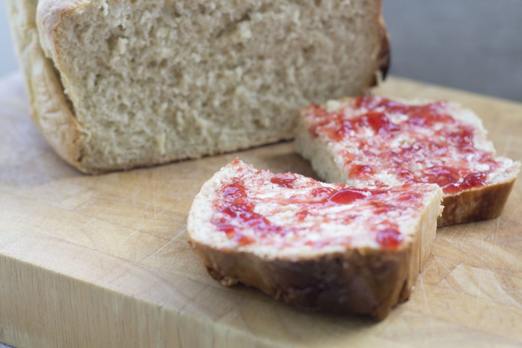 Crock Pot Bread Recipe (How To Make Slow Cooker Bread) 18 a loaf of crock pot bread bread next to a slice of bread spread with butter and jam