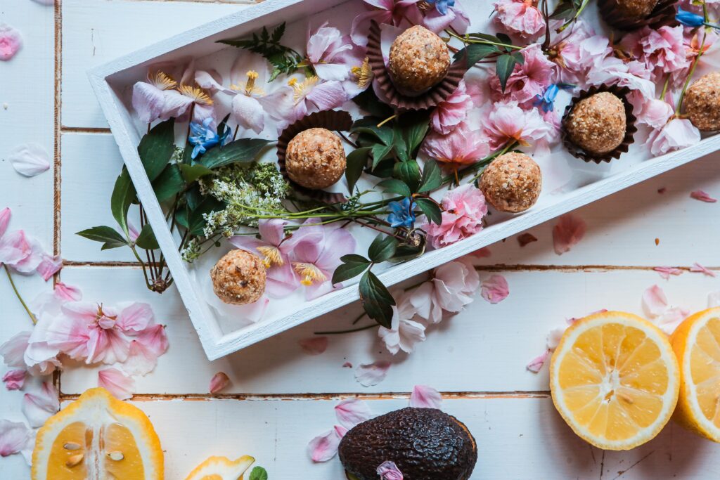 A Vegan Food, Beauty and Lifestyle Blog 29 vegan energy balls on a platter surrounded by flowers and sliced oranges.
