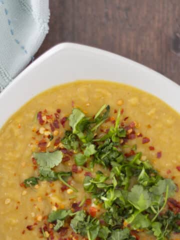 lentil soup in a bowl, topped with chilli flakes and coriander leaves
