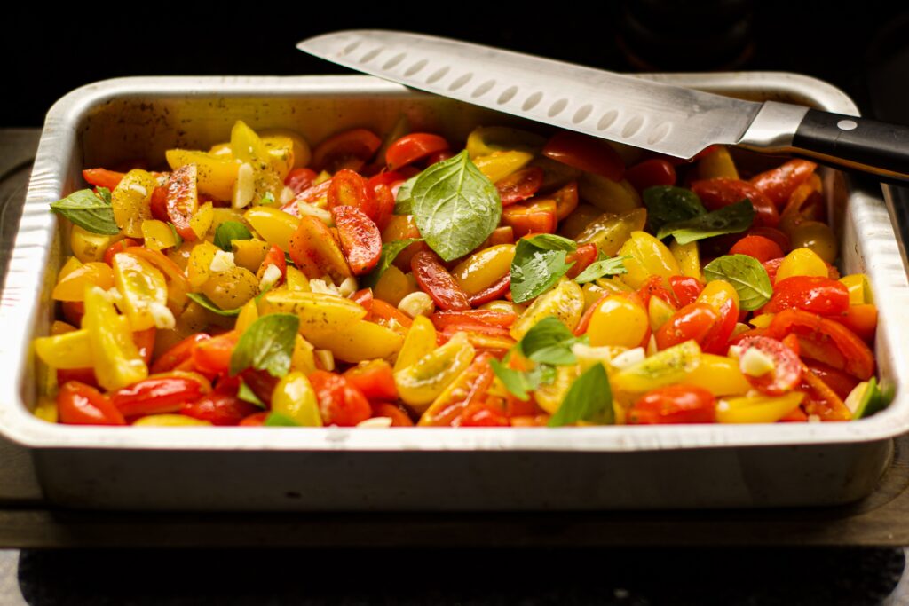 Vegan Family Meal Plan 4th January 2021 3 baking tray full of sliced red and yellow tomatoes, drizzled in oil with basil on the top