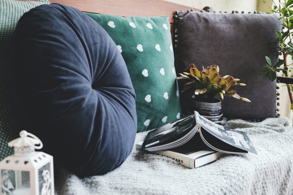 DIY Room Spray With Essential Oils (Homemade Room Freshener) 9 a chair with three cushions, styled with a blanket, a plant and a book