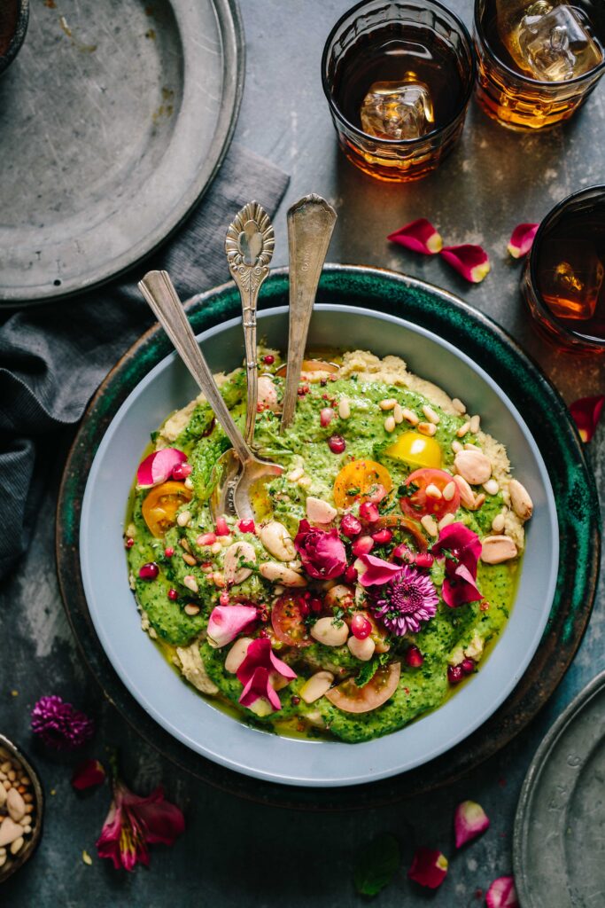 Free Weekly Family Vegan Meal Plan (PDF) 1 a buddha bowl with green pesto, tomatoes, pine nuts, toasted almonds and pink petals.