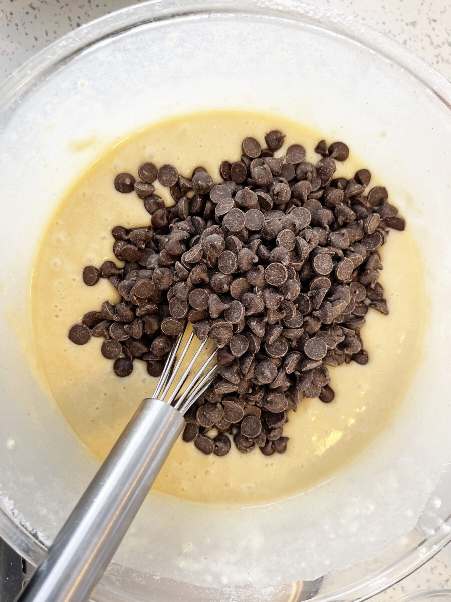 Easy Vegan Chocolate Chip Muffins (Bakery-Style) 193 Muffin batter in a clear mixing bowl with chocolate chips added in.