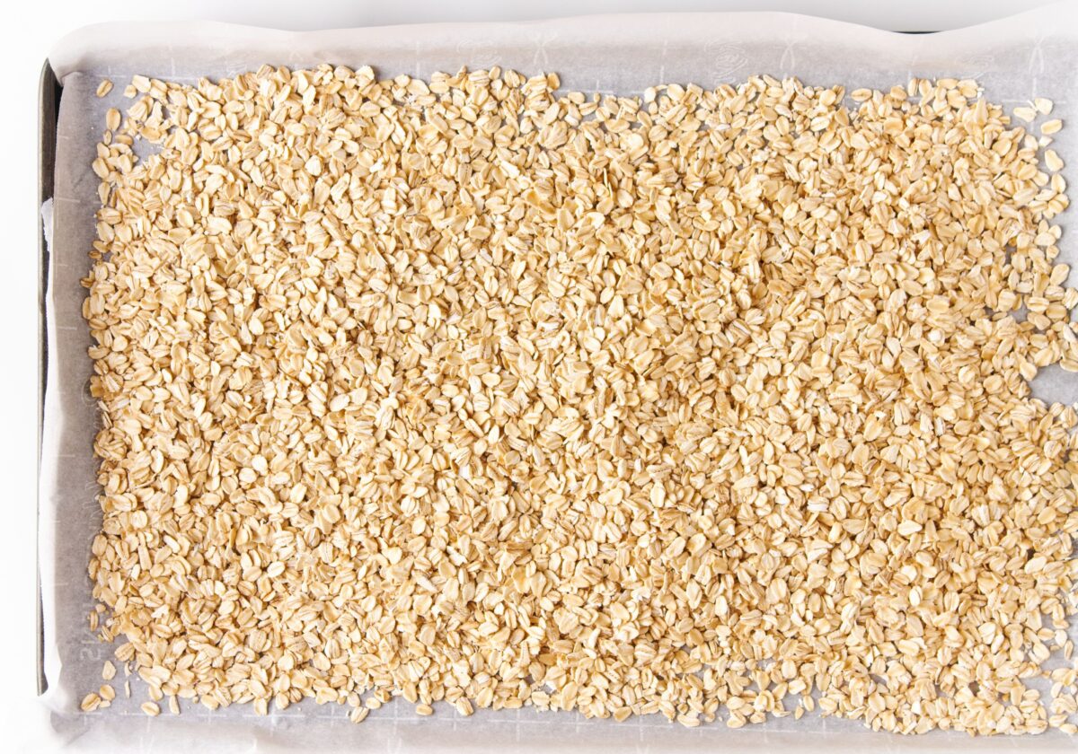 Vegan Strawberry and Cream Granola Protein Bars 215 A baking sheet lined with parchment paper is covered with an even layer of raw oats.