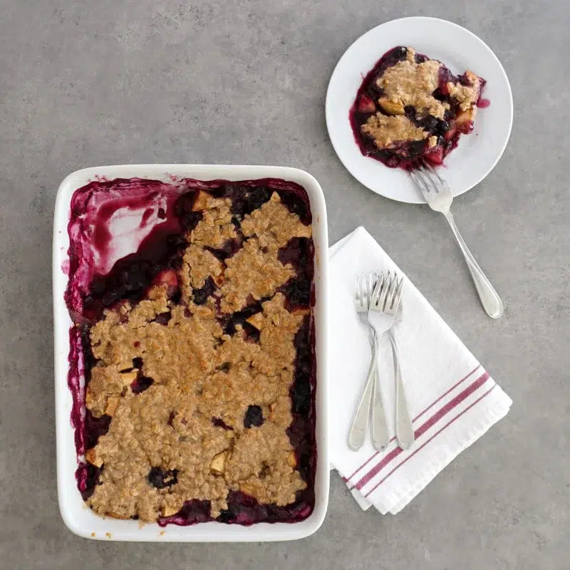 30 Delicious Vegan Blueberry Dessert Recipes 29 Vegan blueberry crisp served on a plate beside the baking dish.