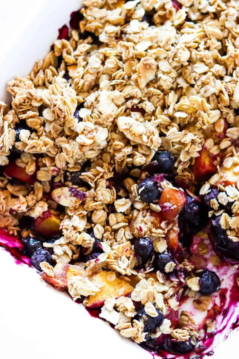 30 Delicious Vegan Blueberry Dessert Recipes 16 Close-up of homemade vegan blueberry peach crisp with a golden crumble topping.