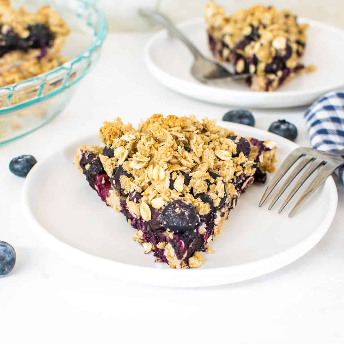 30 Delicious Vegan Blueberry Dessert Recipes 25 Slice of vegan blueberry pie on a white plate with another slice in the background.