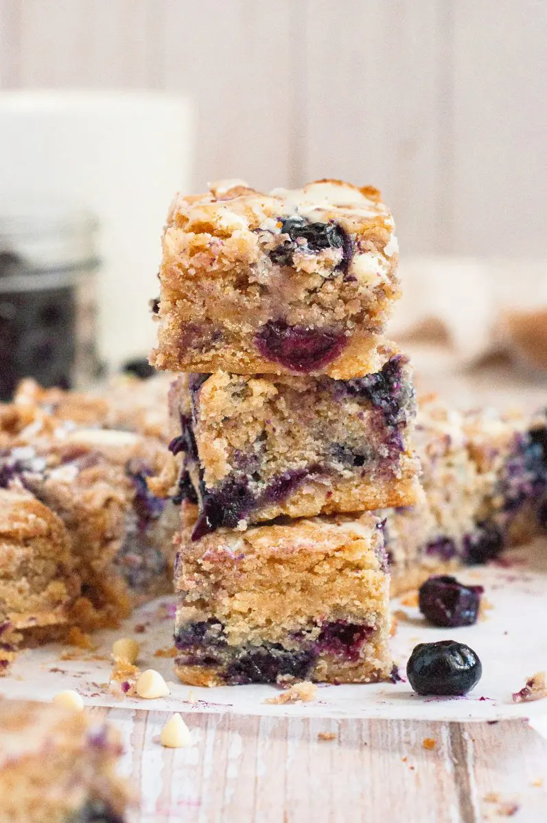 30 Delicious Vegan Blueberry Dessert Recipes 27 Stack of vegan blueberry blondies with more blondies in the background.