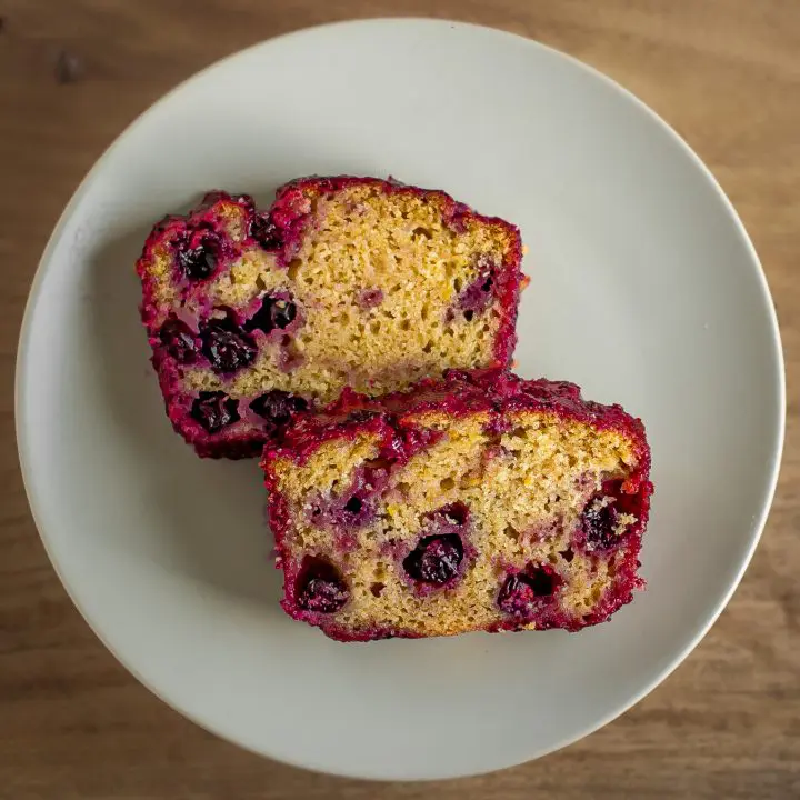 30 Delicious Vegan Blueberry Dessert Recipes 11 Two slices of vegan lemon blueberry cake on a white plate on a wooden table.