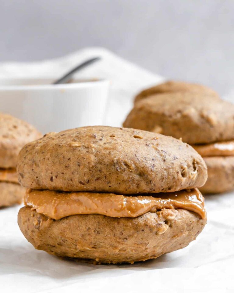 High Calorie Vegan Recipes - Meals For Weight Gain 14 Two high-calorie peanut butter cookies sandwiched with creamy peanut butter filling rest on a parchment paper background, demonstrating a delicious vegan treat.