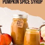 Two jars of pumpkin spice simple syrup sit on a counter, one large with a label and one small. A small pumpkin and autumn leaves decorate the scene. The text "How To Make Pumpkin Spice Syrup" is displayed above.