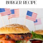 Close-up of a savory black bean and carrot burger, topped with crisp lettuce, juicy tomato, and festive small American flags. Text above invites you to try this delightful Vegan Black Bean and Carrot Burger Recipe.