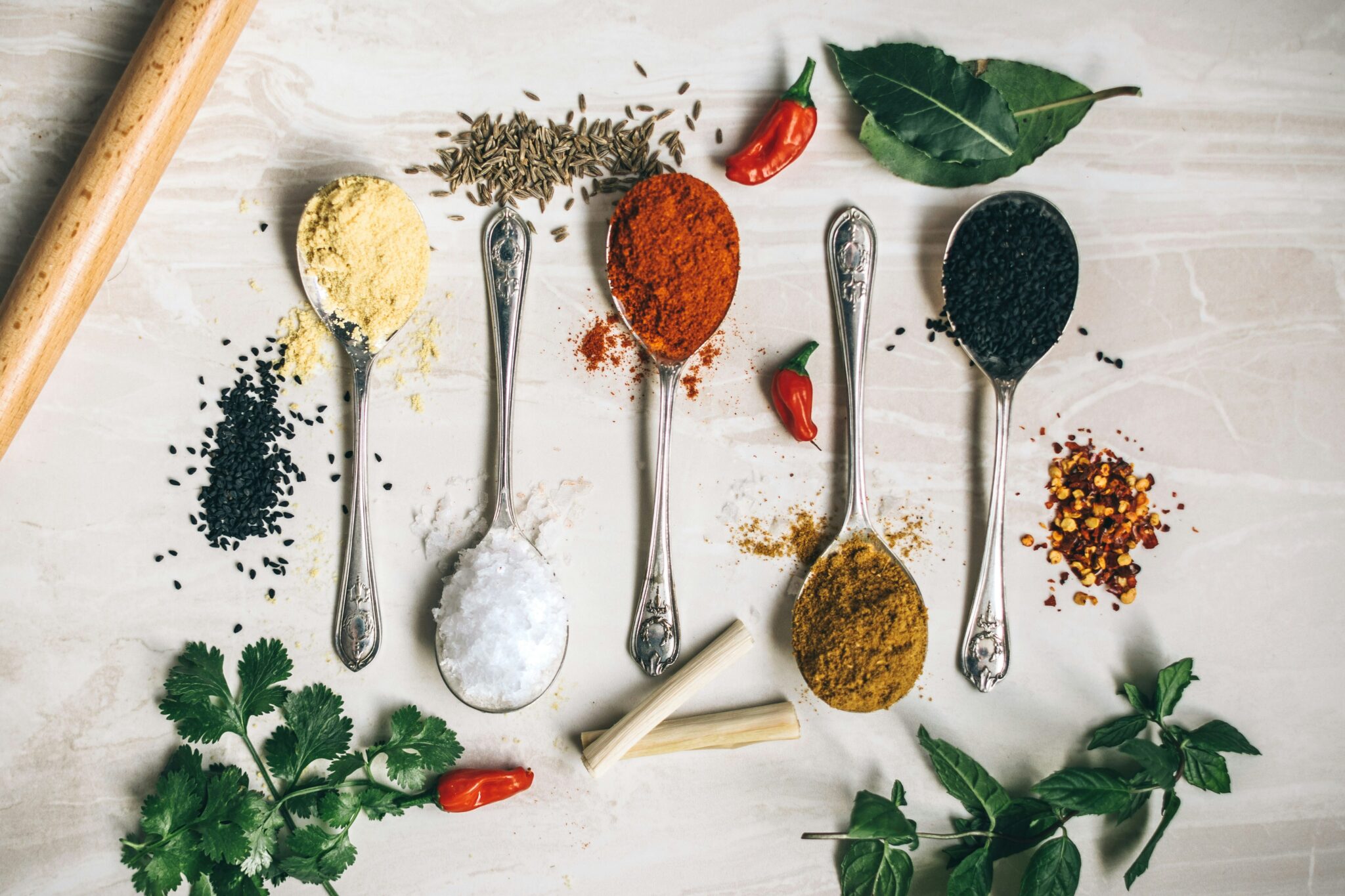 Silver spoons filled with seasonings and herbs for vegan cooking