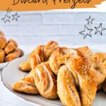 Plate of sourdough discard pretzels with a brown border and doodle stars. Text above reads "Sourdough Discard Pretzels Recipe," inviting you to "get the recipe" with a website link below.