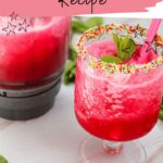 A vibrant watermelon slushie sits in a glass, showcasing its colorful blend. The rim is sprinkled with sugar, topped with a mint garnish and adorned by a pink straw. In the background, a blender hints at the refreshing creation process. Text invites you to "get the watermelon slushie recipe.