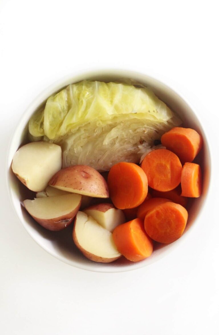 Vegan Irish Recipes For St Patrick's Day 16 A bowl featuring cabbage, red potatoes, and sliced carrots sits on a white background, evoking the essence of Irish recipes perfect for a Vegan St Patrick's Day celebration.