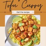 A bowl of creamy vegan tofu curry with yellow rice, garnished with lime wedges and cilantro, with a spoon on the side. Text reads “Vegan Tofu Curry—Get the recipe.”.
