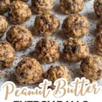 A group of vegan peanut butter balls with chocolate pieces arranged on a white surface, some sprinkled with chocolate shavings.