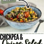 A bowl of high protein quinoa salad with chickpeas, corn, black beans, and tomatoes sits on a white surface with a fork nearby.