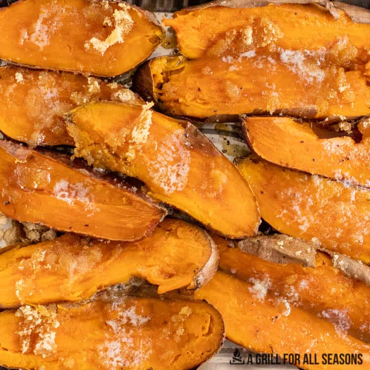 Family-Pleasing Easy Vegan Thanksgiving Recipes 18 Baked sweet potato halves topped with melted butter and brown sugar, arranged on a baking sheet.
