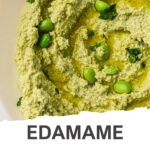 A bowl of edamame houmous, an easy recipe, garnished with whole edamame beans, chopped herbs, and a drizzle of olive oil for a quick and flavourful snack.