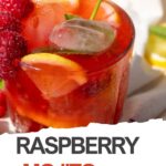 A glass of Raspberry Mojito Mocktail—an easy recipe—features ice, lemon slices, raspberries, and a mint sprig on a light surface. This refreshing alcohol-free drink is perfect for any occasion.