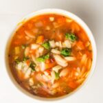 A bowl of vegan minestrone soup with pasta, beans, carrots, tomatoes, broccoli, and leafy greens simmered in a tomato-based broth—perfectly cooked in a slow cooker for rich flavour.